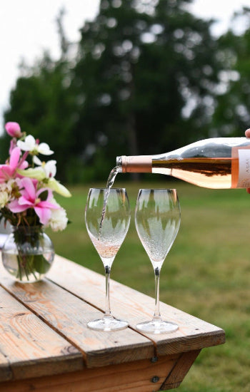 Wine poured from a bottle into 2 glasses on a table